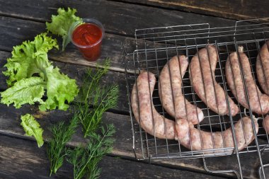 Bir mutfak masası arka plan üzerinde ızgara Rendesi üzerinde Çiğ barbekü sosis.