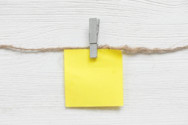 Beyaz bir masa arka plan üzerinde bir ip üzerinde bir clothespin üzerinde kopya alanı ile boş kağıt çıkartmalar. Liste şablonu yapmak için.