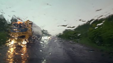 Bulanık bir yol kamyonu yağmur damlaları ile bir araba ön ıslak pencereden karşı şeritte sürüyor.