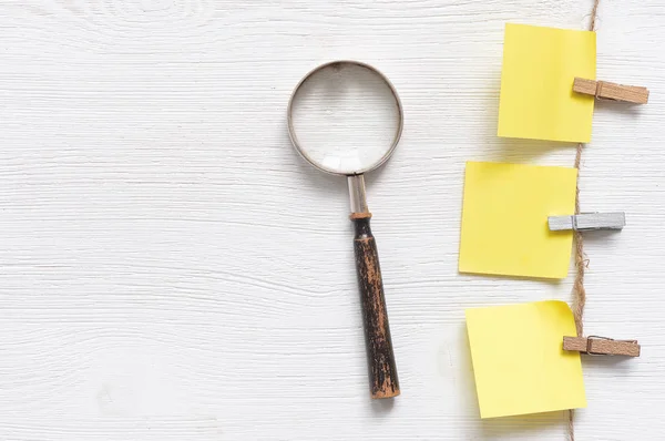 Search list template. Blank paper stickers with copy space and a magnifying glass on a white table background.