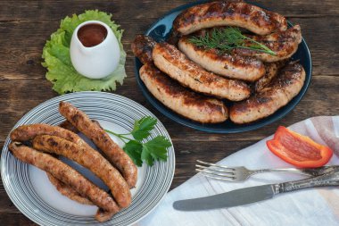 Mutfak masası arka planında bir tabakta ızgara sosis.