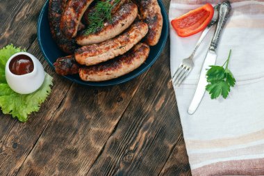 Mutfak masası arka planında bir tabakta ızgara sosis.