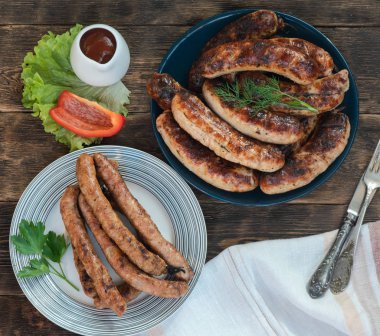 Mutfak masası arka planında bir tabakta ızgara sosis.