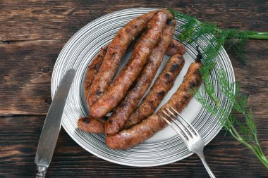 Mutfak masası arka planında bir tabakta ızgara sosis.