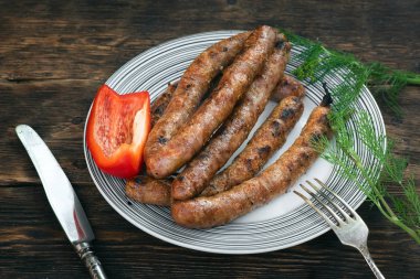 Mutfak masası arka planında bir tabakta ızgara sosis.