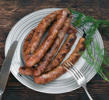 Mutfak masası arka planında bir tabakta ızgara sosis.