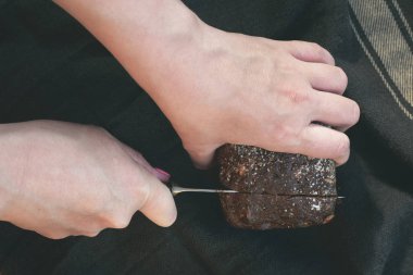 Kadın, kesme tahtasında mutfak bıçağıyla taze ekmek kesiyor..