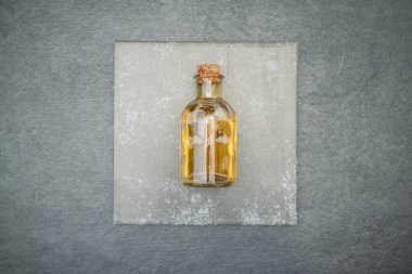 Temel yağ ürünü ya da aromaterapi yağı gri arka plandaki şişede yatıyordu..
