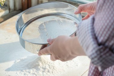 Kadın mutfak masasında un seçiyor. Yakından..