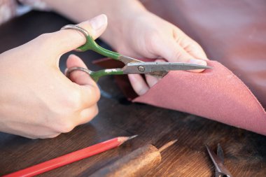 Kadın terzi deriyi makasla kesiyor..