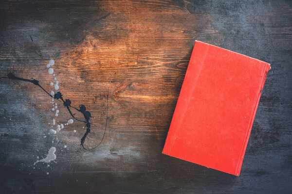 Old red book on dark wooden flat lay background with copy space.