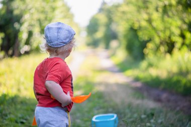 Bir yaşındaki erkek bebek dışarıdaki yeşil çimlerde oynuyor..