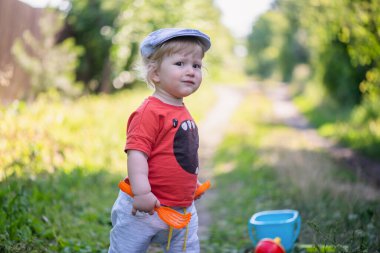 Bir yaşındaki erkek bebek dışarıdaki yeşil çimlerde oynuyor..