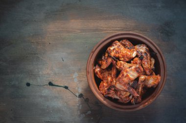 Char Izgara Tavuk Kanatları eski masa arkasında tabakta.