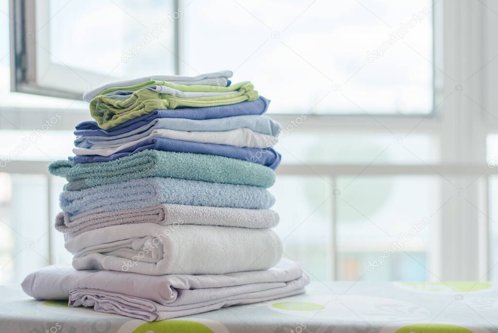 Stack of clean clothes on ironing board close up.