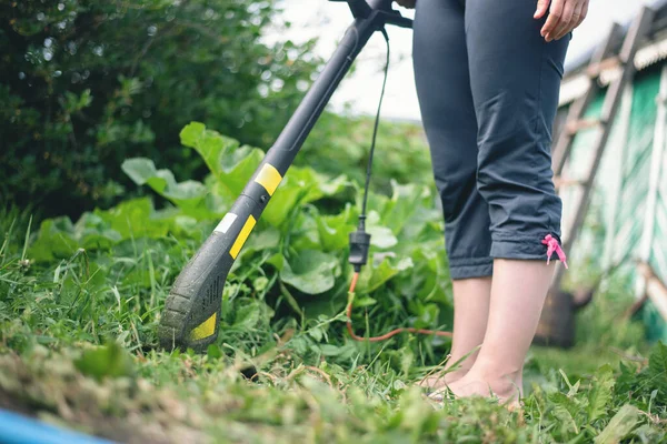 Gardener working with a garden trimmer close up.