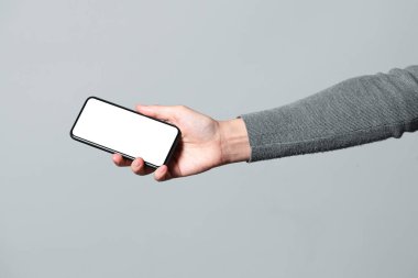 Gri arkaplanda kadın eli ile kopyalama alanı olan cep telefonu.