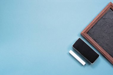 Tahta çerçeve, tebeşir ve sünger mavi arka planda. Eðitim düzlüğü kopyalama alanı ile yatar.