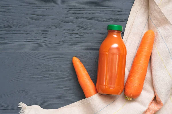 Carrot juice in a bottle on gray wooden table flat lay background.