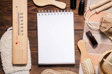 Banyo aksesuarları ve kahverengi ahşap düz arka planda fotokopi alanı olan boş bir sayfa defteri. Hijyen konsepti. Hamam ipuçları uydurma..