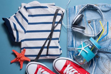 Kırmızı sakız, kot şort, gömlek, kırmızı denizyıldızı, kulaklık ve mavi arka planda tüp olan kokteyl kavanozu. Yaz tatili geçmişi.