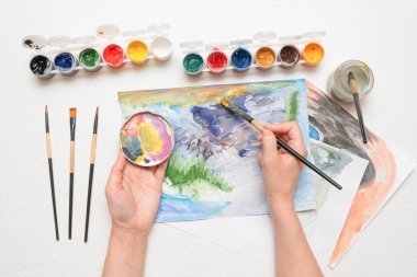 Amatör bir ressam beyaz masa üzerine guaj boyasıyla resim çiziyor..