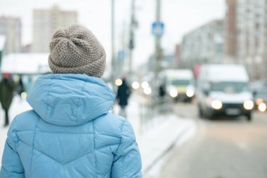 Kışın otobüs durağında bekleyen bir kadın..
