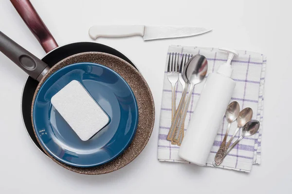 Dishes, white bottle of detergent, sponges and towel on white flat lay background. Washing up concept.