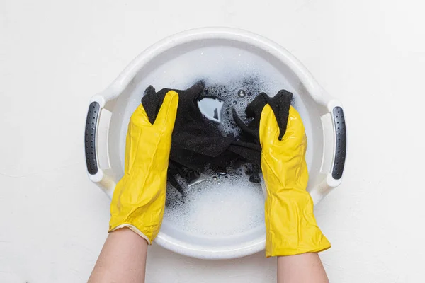 Female hands holding a wash basin with foam water flat lay background. Hand wash concept.