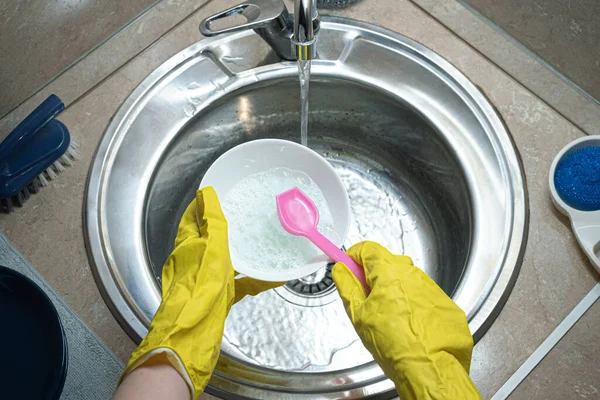 Woman is washing a dishes by the brush in the kitchen sink. Dish washing, washing up concept.