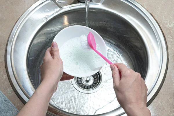 Woman is washing a dishes by the brush in the kitchen sink. Dish washing, washing up concept.