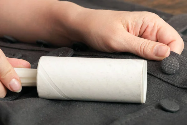 Woman cleans clothes with a cleaning roller close up.