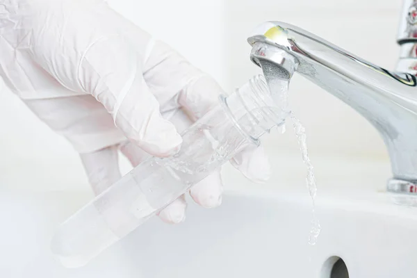 Musluk suyu analiz kalite kontrol kavramı. Elinde matara ve musluk musluğu olan bir el..