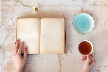 Kitap okuyan ve sıcak çay içen bir kadın..