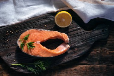 Tahta üzerinde çiğ somon bifteği, dolma biber ve dereotla birlikte..