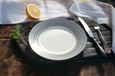 Eski bir ahşap tekmeleme masasının arka planında kesilmiş tahtada yiyecek için kopyalama alanı olan boş tabak.