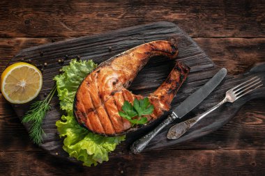 Ahşap mutfak masasının arka planında ızgara somon bifteği..