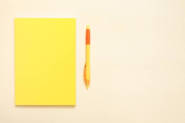 Turuncu arka planda sarı not defteri ve kalem.