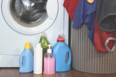 Çamaşır makinesi, çamaşır deterjanı şişeleri ve sepette kirli çamaşırlar..