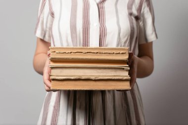 Öğrenci elinde bir yığın eski kitap tutuyor..