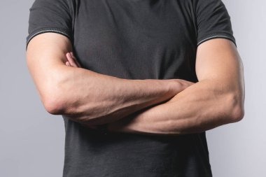 Gri arka planda kolları çapraz duran bir adam..