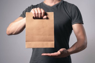 Gri arka planda, erkek elinde bir alışveriş çantası..