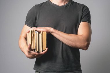 Gri arkaplanda kopya alanı ile izole kitap yığınına sahip öğrenci.