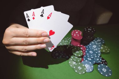 Masada poker fişleri ve dört aslı bir kadın eli var..