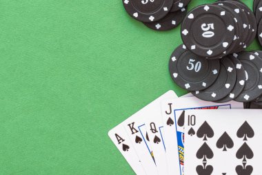 Yeşil düz zemin üzerinde Royal Floş kartları ve poker çipleri.