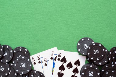 Yeşil düz zemin üzerinde Royal Floş kartları ve poker çipleri.