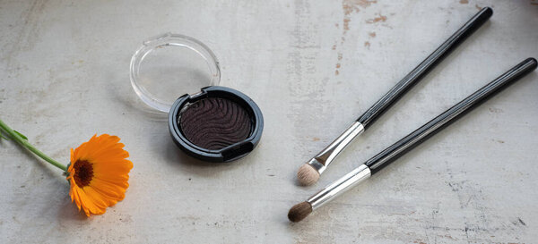 Тени для век в банке с кисточками для макияжа на белом деревянном фоне
.