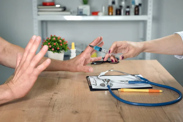 Tedaviyi ya da aşıyı reddetmek. Enjeksiyon korkusu. Zorunlu tedavi konsepti. Şırıngalı bir doktor ve korkmuş bir hasta..