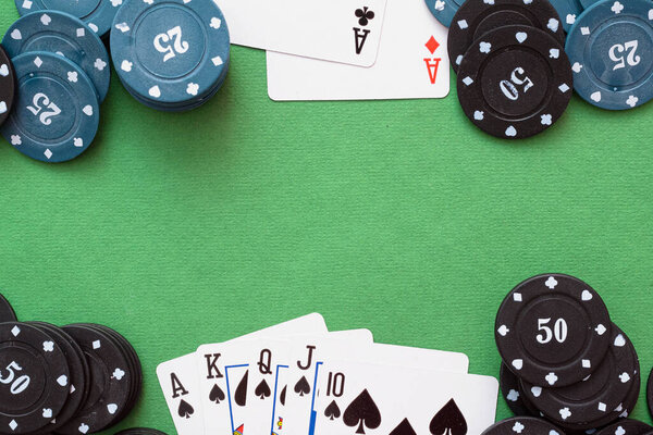 Royal Flush cards and poker chips on green flat lay background.