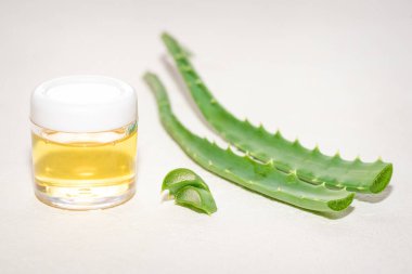 Aloe vera yaprakları ve beyaz arka planda gerekli yağ kavanozu.